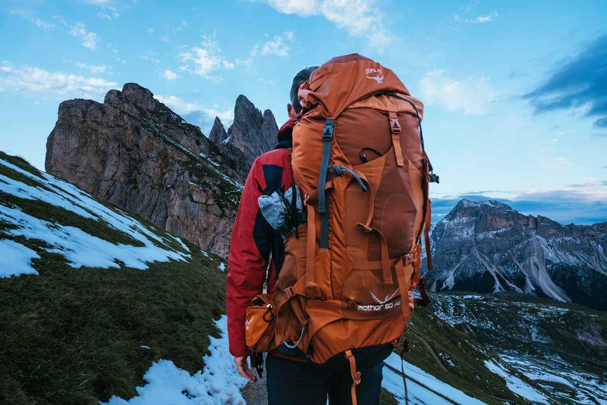 Hiker wearing multi-day backpacks on a trail.