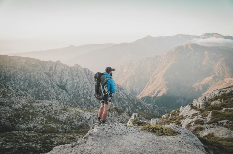 Multi-Day Hiking Gear: What You Actually Need (And What to Skip) A hiker with a loaded backpack walking along a rocky mountain trail.